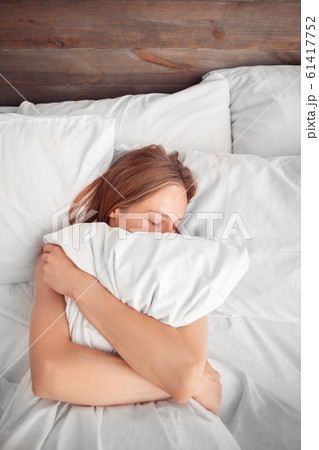 Morning at Home. Woman lying on bed hugging pillow sleeping top view Morning at Home. Woman lying on bed hugging pillow sleeping top view 61417752