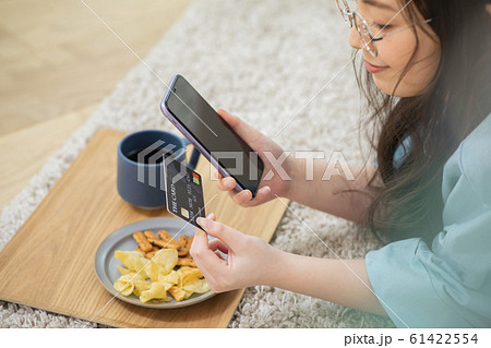 女性　ニット　寝転ぶ　スマホ　スマートフォン　携帯　携帯電話　カード　クレジットカード 61422554