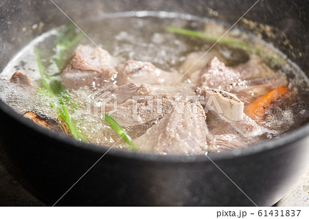 Traditional beef broth with vegetable, bones and ingredients in pot, cooking recipe. Soup in a cooking pot with ladle on dark stone background. Top view Traditional beef broth with vegetable, bones and ingredients in pot, cooking recipe. Soup in a cooking pot with ladle on dark stone background. Top view 61431837