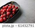 Fresh cherries covered with water droplets in a black bowl on a dark background. 61432791