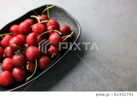 Fresh cherries covered with water droplets in a black bowl on a dark background. Fresh cherries covered with water droplets in a black bowl on a dark background. 61432791