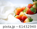 Fresh strawberries in a white cup, Put on the white fabric backing pad, On the white table. 61432940