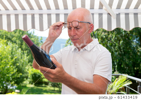 mature man with bottle of red wine, on the terrace 61433419