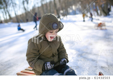 Boy sledding on the street in the snowy winter in the mountains Boy sledding on the street in the snowy winter in the mountains 61438503