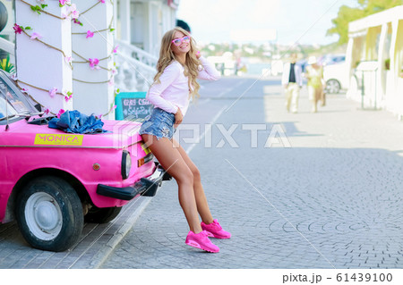 Sexy woman in short denim shorts near bright pink car 61439100