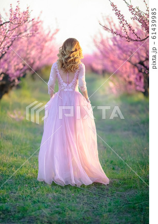 Full-length outdoor model in a garden in nature in pink colors. Full-length outdoor model in a garden in nature in pink colors. 61439985