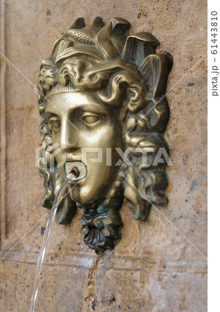 a small fountain in the form of the head of a Medusa Gorgon 61443810