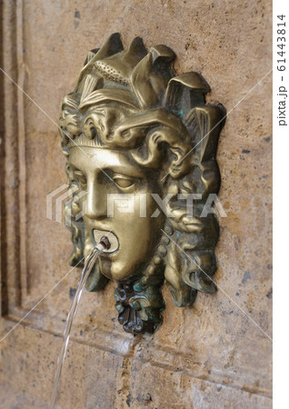 a small fountain in the form of the head of a Medusa Gorgon 61443814