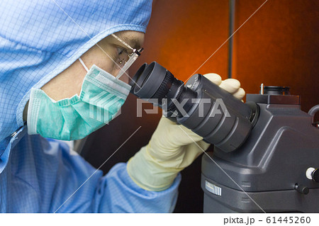 The inspector making incoming check on microscope in clear room. The inspector making incoming check on microscope in clear room. 61445260