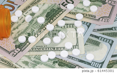 White pills spill out of container onto money 61445301