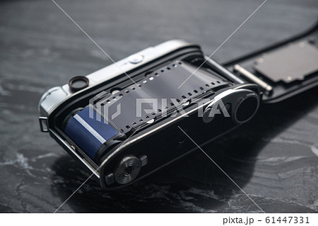 Vintage analog film camera with a lens and a charged film on a marble stone background. 61447331