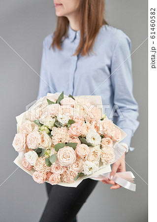 Mono bouquet of spray roses. Delicate bouquet of mixed flowers in womans hands. the work of the florist at a flower shop. Delicate Pastel color. Fresh cut flower. 61460582