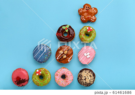 Sweet colored donuts on a blue background, laid out in the form of various geomitric figure, arrow, square, line, triangle, top view. Desserts, game of colors, blue background. 61461686