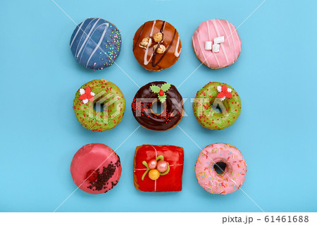Sweet colored donuts on a blue background, laid out in the form of various geomitric figure, arrow, square, line, triangle, top view. Desserts, game of colors, blue background. 61461688