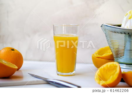 On a wooden table, one whole orange, one cut in half, peel of an orange. On the table lies a stone board and a knife. In the background is a glass cup with freshly squeezed orange juice. On the right 61462206