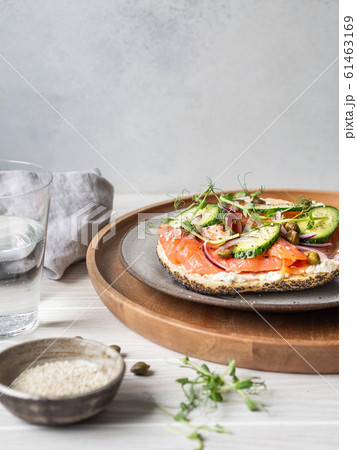 Healthy toast with cream cheese, salmon, fresh cucumber, capers, red onion, black pepper and pea sprouts on plate. Copy space Healthy toast with cream cheese, salmon, fresh cucumber, capers, red onion, black pepper and pea sprouts on plate. Copy space 61463169