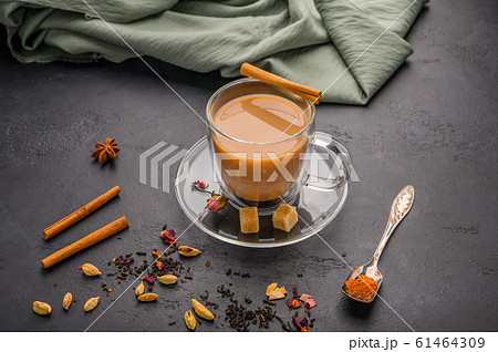 Traditional Indian masala tea chai. Cinnamon, anise, cardamom, sugar next to a black textured 61464309