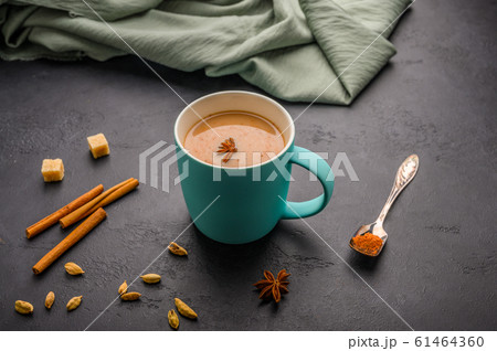 Traditional Indian masala tea chai in a blue cup. Cinnamon, anise, cardamom, sugar next to a black Traditional Indian masala tea chai in a blue cup. Cinnamon, anise, cardamom, sugar next to a black 61464360