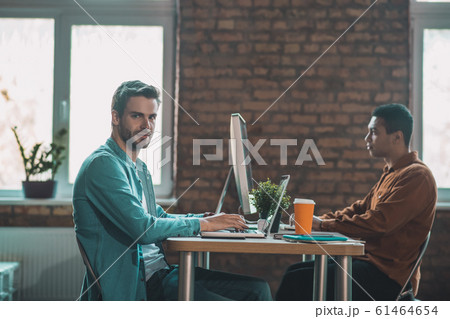 Intelligent bearded man sitting opposite his colleague 61464654