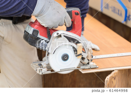 床材を電動丸ノコでカットしている職人の手元クローズアップ 61464998