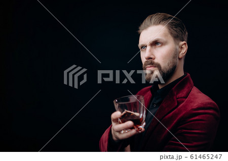 Handsome Virile Male in Vinous Jacket Holding a Glass of Spirits 61465247