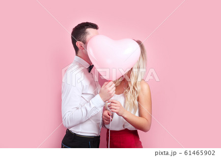 Couple holding heart shaped air balloon and kissing. Couple holding heart shaped air balloon and kissing. 61465902