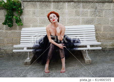 A beautiful girl with white skin and bright red hair poses in the image of Marilyn Monroe. 61466505