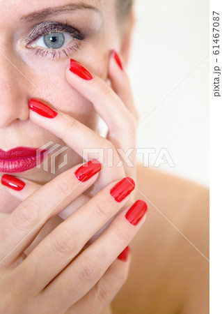 A beautiful young woman is touching her face with her fingers 61467087