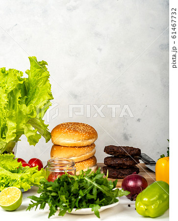 Big burgers with cutlet, cheese and herbs on white background in the kitchen. Big burgers with cutlet, cheese and herbs on white background in the kitchen. 61467732