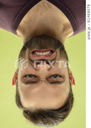 Inverted portrait of caucasian young man on yellow studio background Inverted portrait of caucasian young man on yellow studio background 61468078