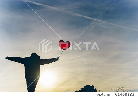 Man from the back with a red balloon in hand against the blue sky on frosty day 61468233