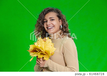 Welcome autumn concept. Smiling girl holds yellow maple leaves, enjoying the season. 61468728