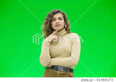 Thoughtful girl in casual clothes, keeping finger on cheek, looking lost in thoughts. 61469173