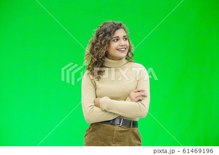 Happy young woman with a cute smile standing on green background with copy space. Happy young woman with a cute smile standing on green background with copy space. 61469196