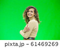 Happy young woman with a cute smile standing on green background with copy space. 61469269