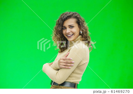 Beautiful woman with kinky hair in beige clothes, isolated on green, looking pleased. 61469270