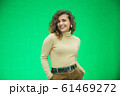 Glowing girl posing on green background, looking positive, smiling. 61469272
