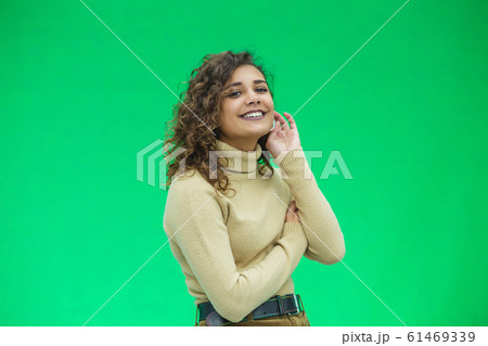 Portrait of gorgeous female model posing in white fashion clothes in studio over green background. 61469339