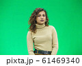 Beautiful woman with kinky hair in beige clothes, isolated on green, looking pleased. 61469340