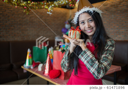 beautiful woman wear red dress and santa claus hat showing golden gift box on hand in restaurant. concept of Christmas party and New year party with copy space for text. beautiful woman wear red dress and santa claus hat showing golden gift box on hand in restaurant. concept of Christmas party and New year party with copy space for text. 61471896