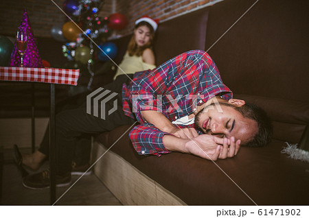 Asian man and women are very drunk sleeping on the couch after the party ended. concept of Xmas party, Christmas party and New year party celebration. 61471902