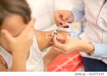 Shot of human hands making an injection to a child 61475145