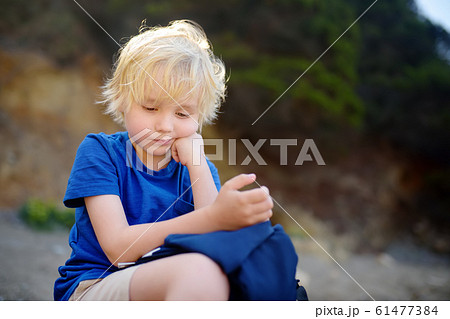 Little boy is bored during walking on nature. Sad child Little boy is bored during walking on nature. Sad child 61477384