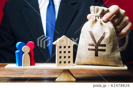 Man puts Yen yuan money bag and house on scales with a family. Mortgage, debt burden. Assistance with housing and financing for young families to stimulate childbirth demographic population growth. 61478626