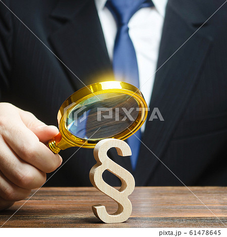 A man examines a paragraph figure with a magnifying glass. Judicial practice. Legitimacy. Studying laws and legislation, norms, rules. Legal service, lawyer services. Protection of rights, interests. 61478645