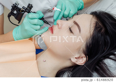Woman having permanent makeup on lips Woman having permanent makeup on lips 61486920