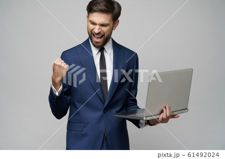 Young handsome businessman Holding a laptop Computer with Blank Screen 61492024