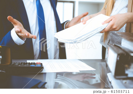 Bookkeeper or financial inspector and secretary making report, calculating or checking balance. Internal Revenue Service inspector checking financial document. Audit concept Bookkeeper or financial inspector and secretary making report, calculating or checking balance. Internal Revenue Service inspector checking financial document. Audit concept 61503711