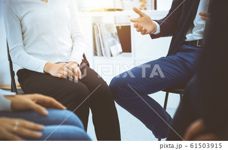 Group of people sitting in a circle during therapy in sunny office. Meeting of business team participating in training Group of people sitting in a circle during therapy in sunny office. Meeting of business team participating in training 61503915