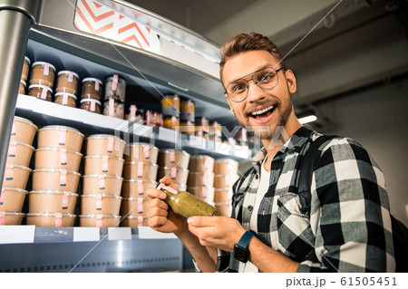 Happy young man is standing in supermarket 61505451